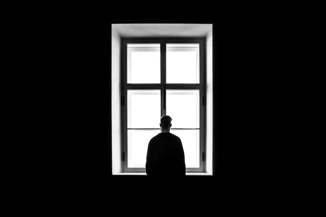 Person in quiet solitude near a window representing grief and loss