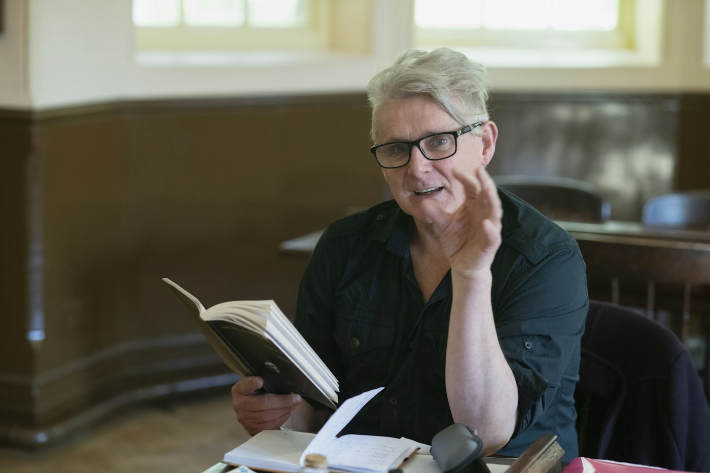 An older man seated at a table reading a book.